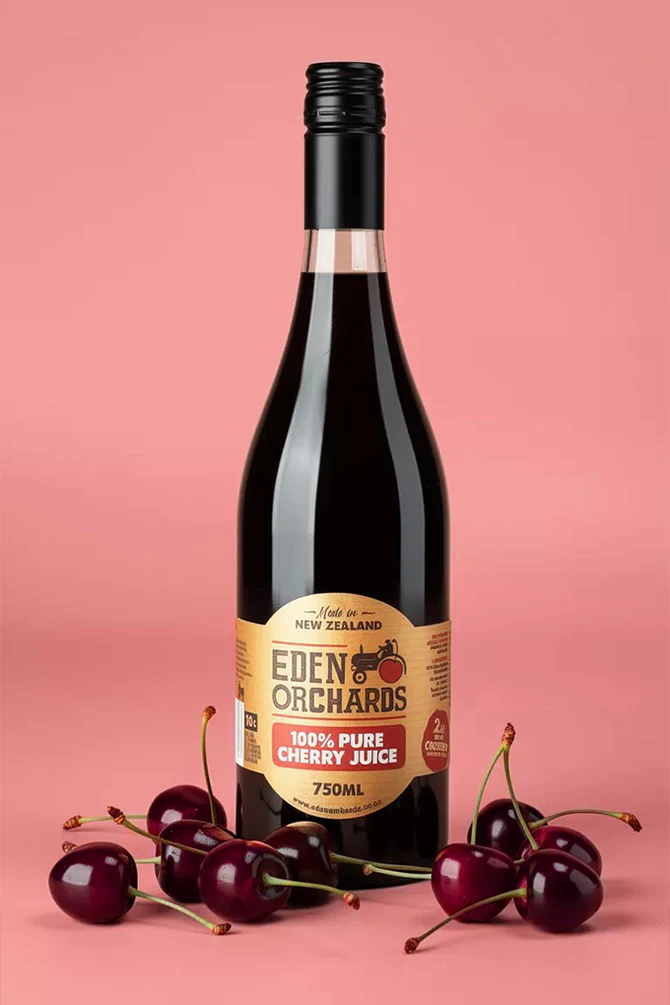 A 750ml bottle of Eden Orchards Pure Cherry Juice with fresh cherries